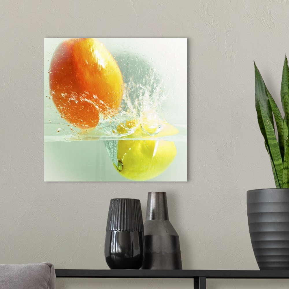 A modern room featuring an orange and a lemon dropped in water and captured during a splash. color and square format image