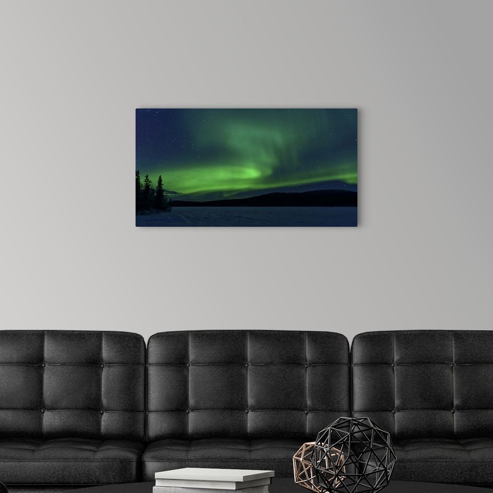A modern room featuring The green light of the Northern Lights (aurora borealis) sparkle above a snow covered frozen lake...