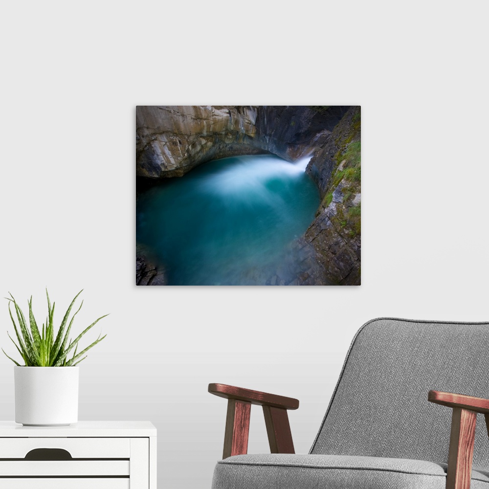 A modern room featuring Johnson Canyon, Banff National Park, Canada.  The base of a waterfall flowing into a turquoise pool.