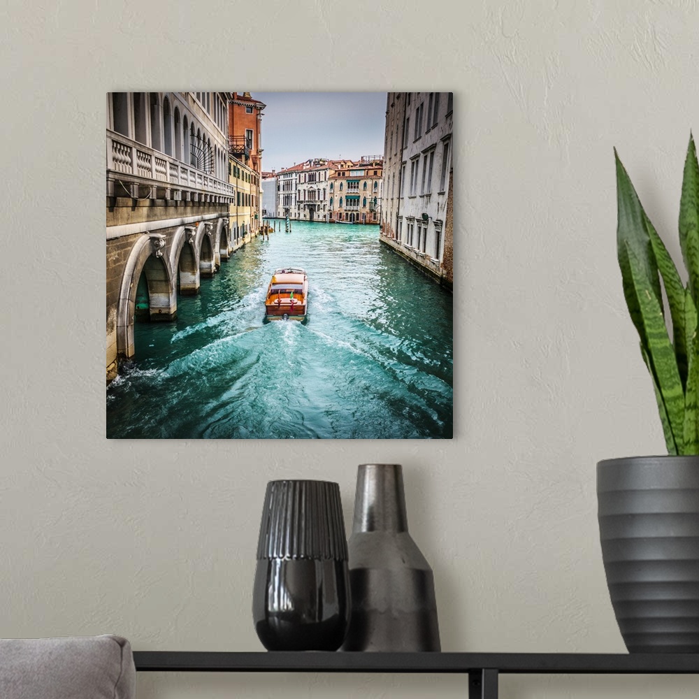 A modern room featuring water taxi in a side canal of Venice about to join the Grand Canal.