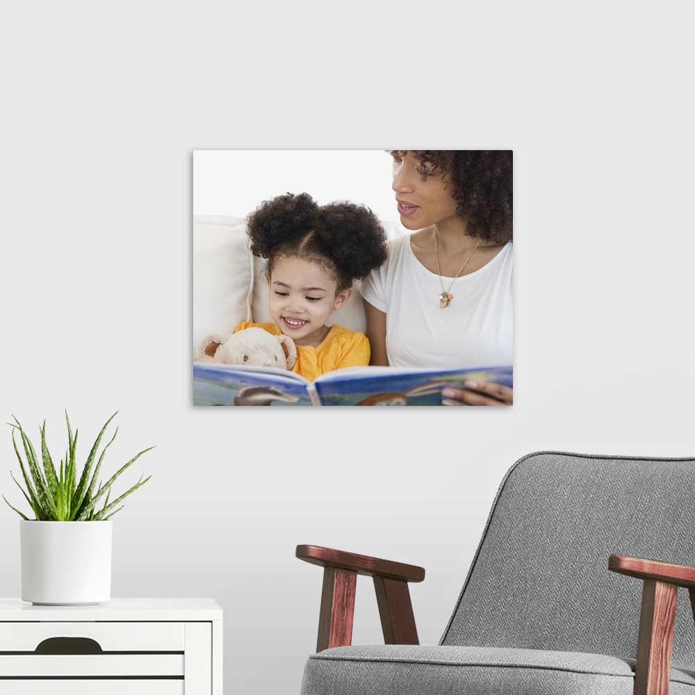A modern room featuring Woman reading book with daughter