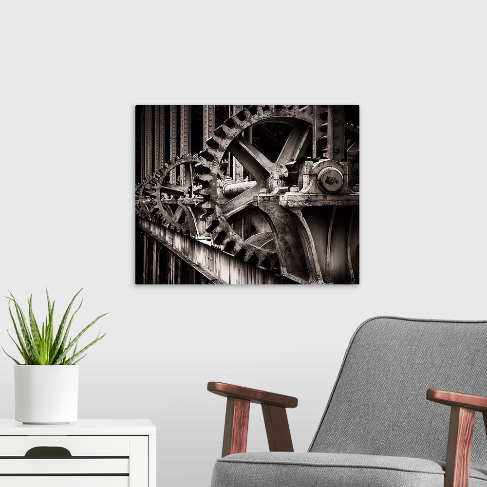 A modern room featuring A photograph of a set of large old looking gears that operate a gate.