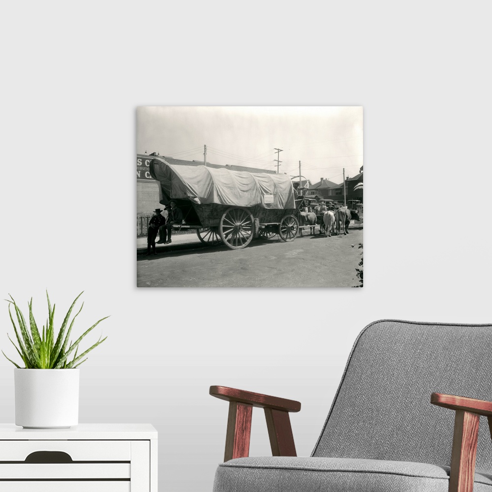 A modern room featuring 1920's Ox Drawn Conestoga Covered Wagon Parked Along Street.