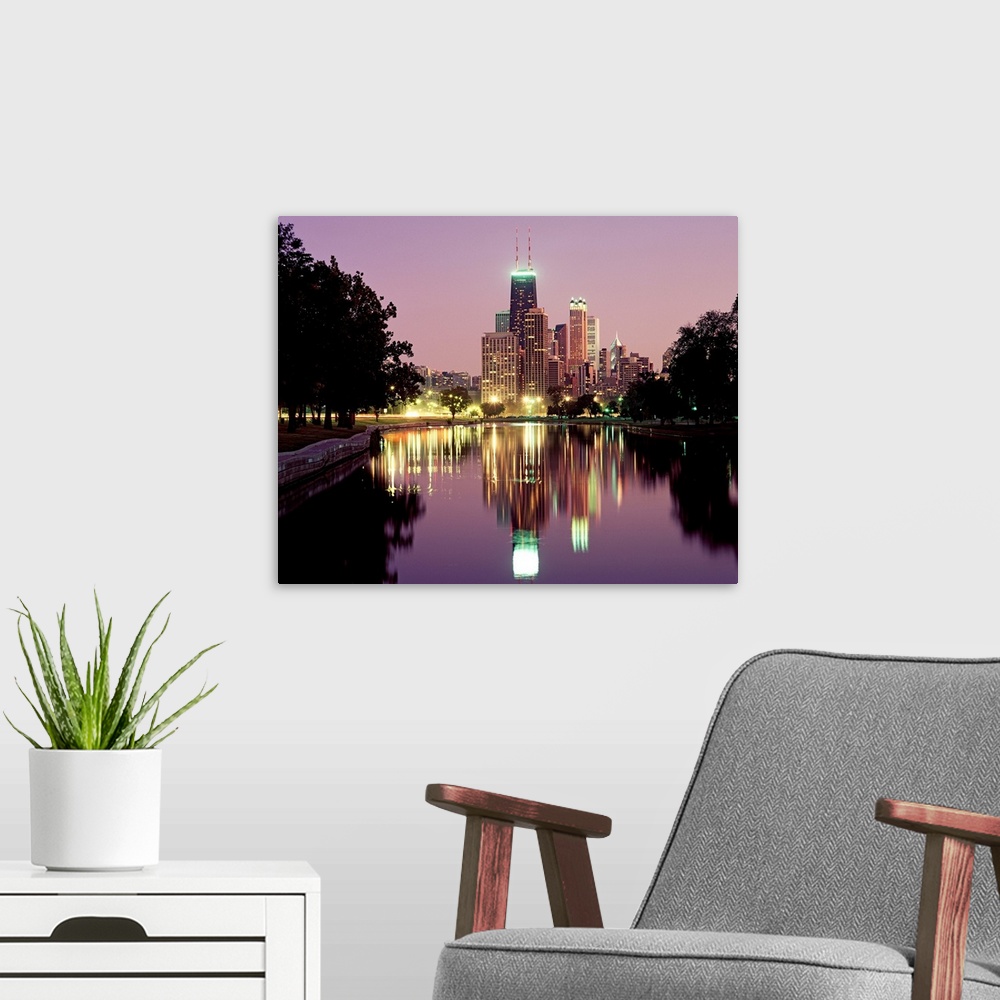 A modern room featuring Oversized photograph wall art of city lights and skyscrapers reflecting in a pond in a park.