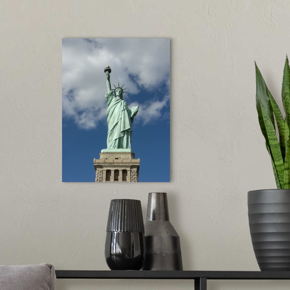 A modern room featuring Vertical, low angle photograph on a big canvas, looking up at the Statue of Liberty against a blu...