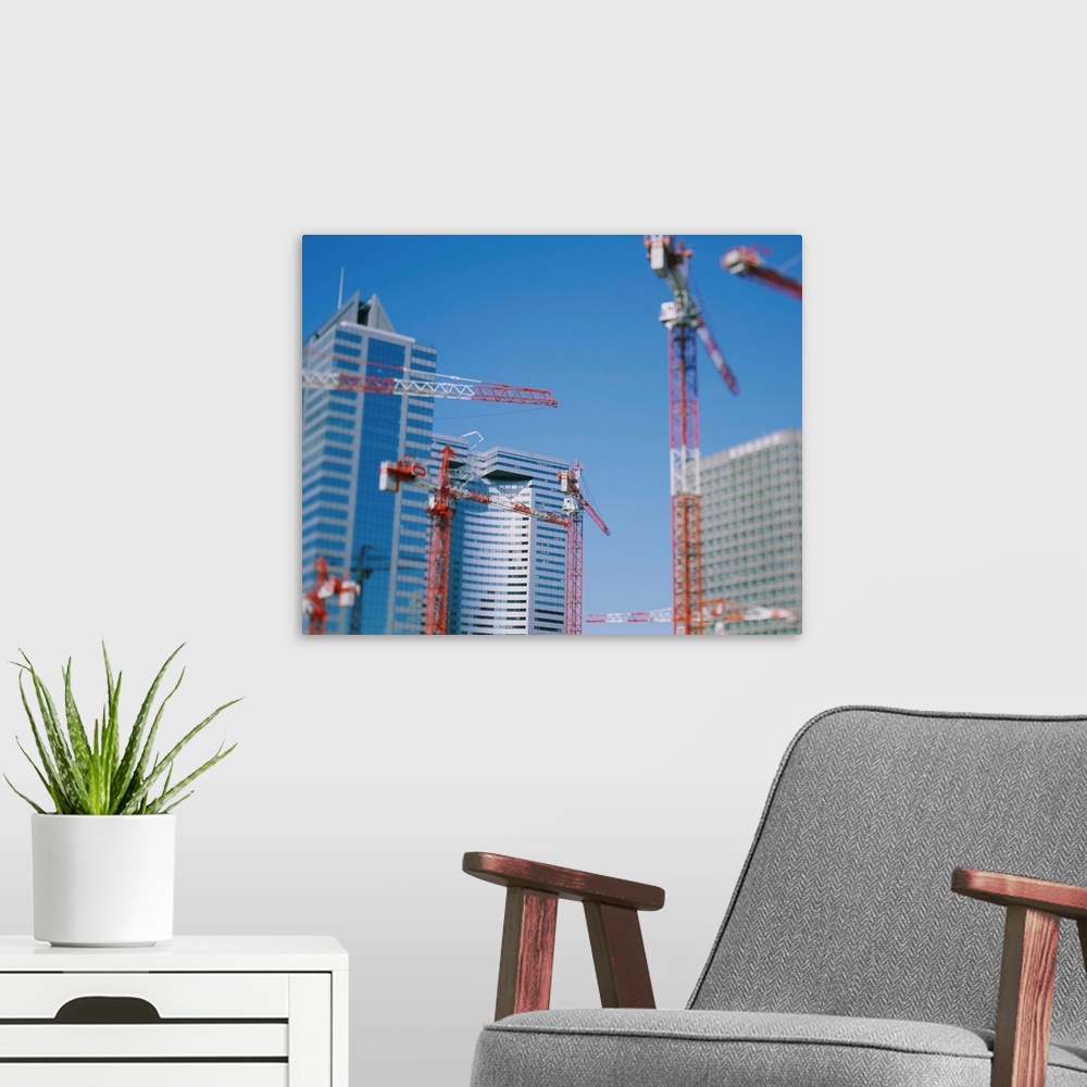 A modern room featuring Low angle view of cranes in front of buildings