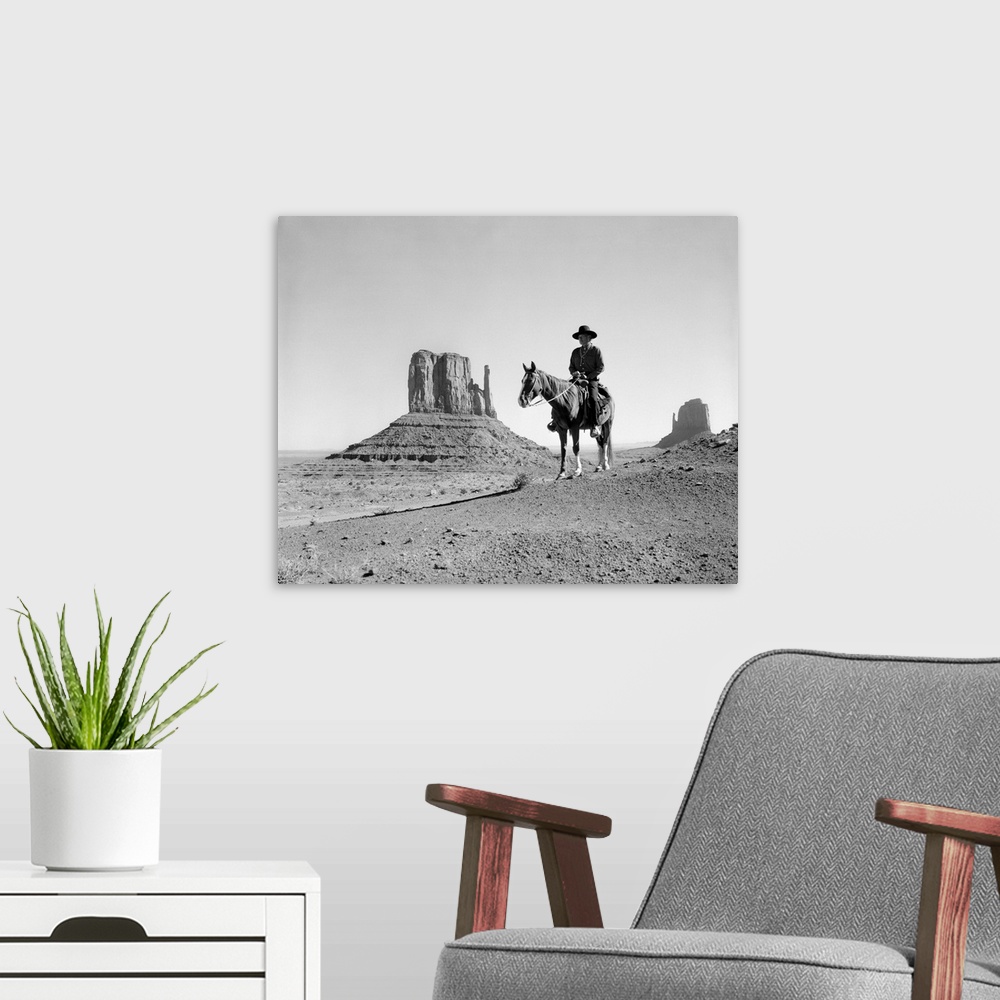A modern room featuring Navajo indian in cowboy hat on horseback with monument valley rock formations in background.