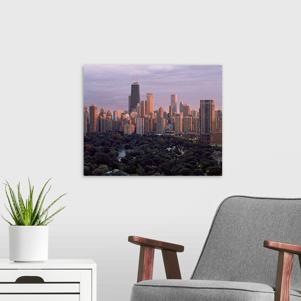 A modern room featuring This twilight photograph of the downtown shows the interior of a city park and many major city sk...