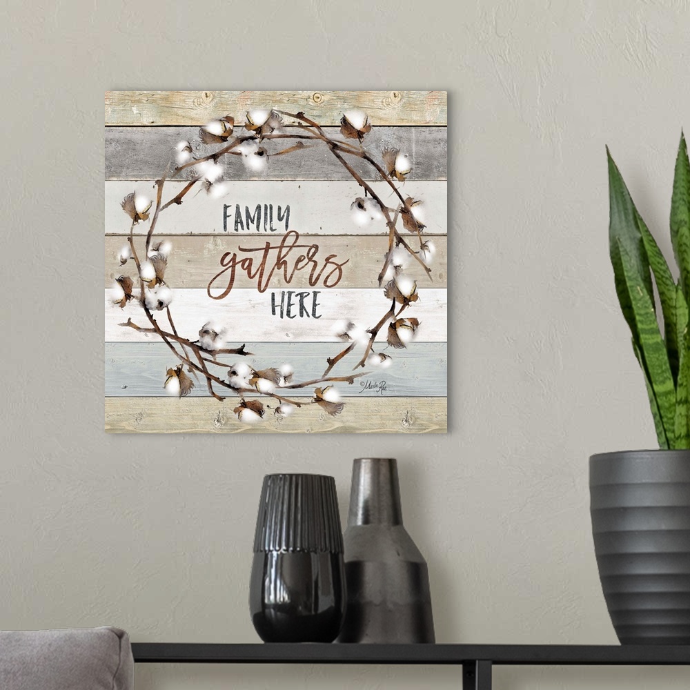 A modern room featuring "Family Gathers Here" in the middle of a wreath of cotton against a shiplap background.