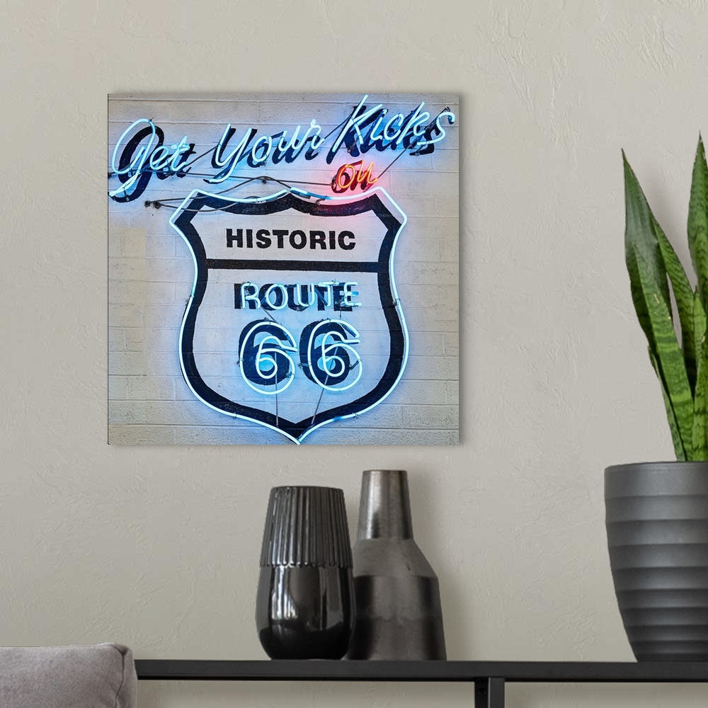 A modern room featuring Square photograph of a neon Route 66 sign on a wall.