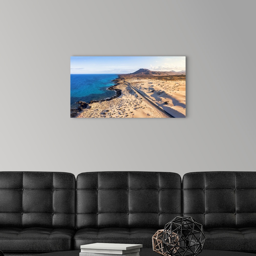 A modern room featuring Empty road crossing the sand dunes overlooking the ocean, Corralejo Natural Park, Fuerteventura, ...