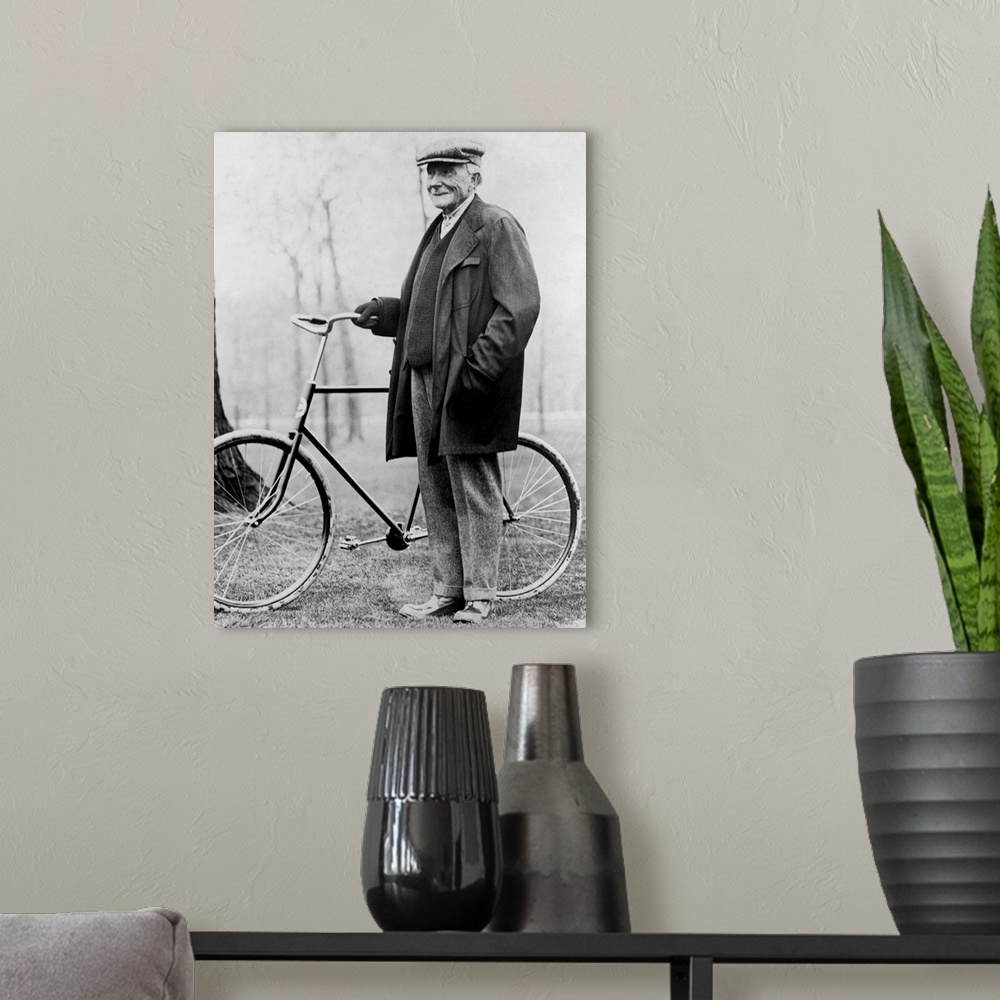 A modern room featuring American business magnate John D. Rockefeller standing beside a bicycle in 1913.