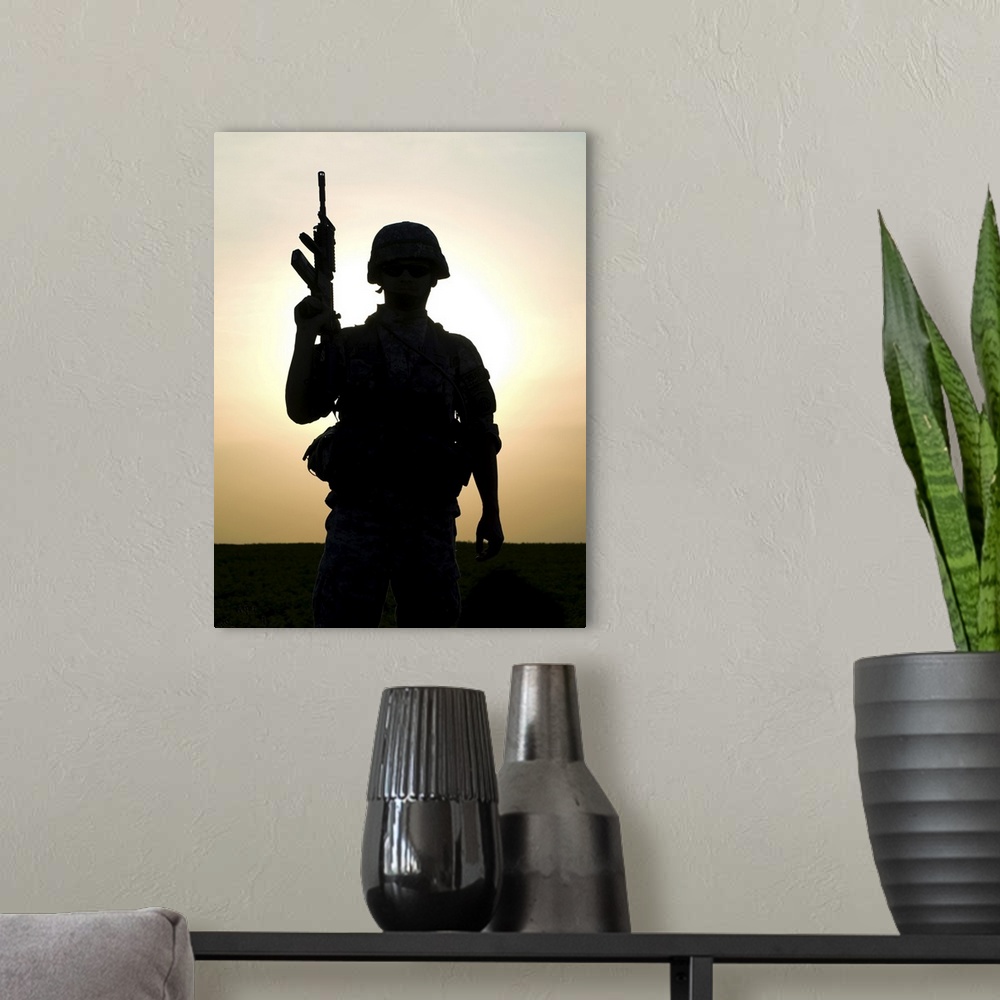 A modern room featuring Silhouette of U.S. soldier with rifle against a sunset.