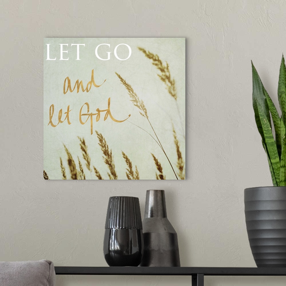 A modern room featuring Square photograph of the tips of beach grass swaying in the wind with the quote "Let Go and Let G...