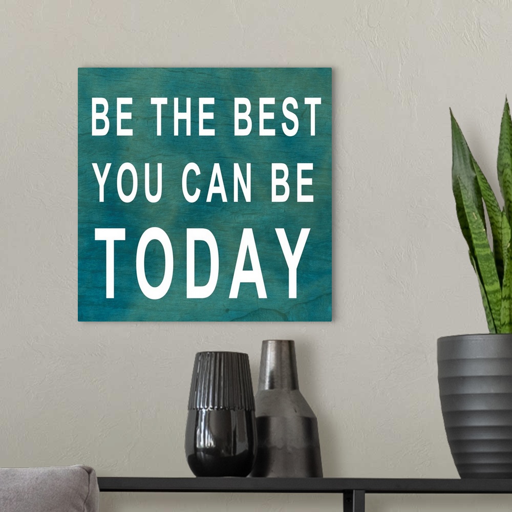 A modern room featuring Square, large inspirational artwork of big text that reads "Be the best you can be today", on a b...