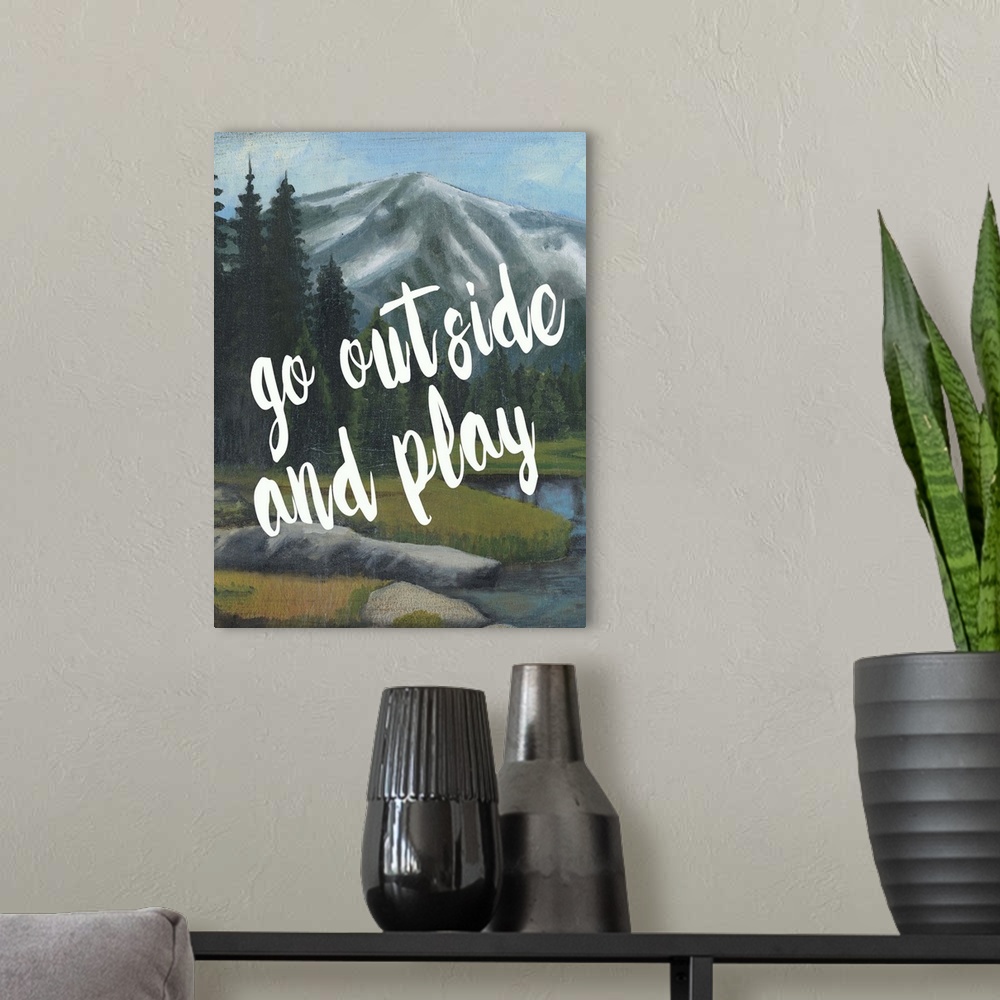A modern room featuring White handlettered text reading "Go outside and play" over a painting of a mountain landscape.