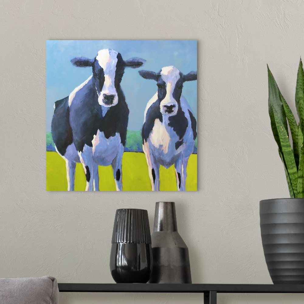 A modern room featuring Contemporary painting of two black and white dairy cows in a green field.