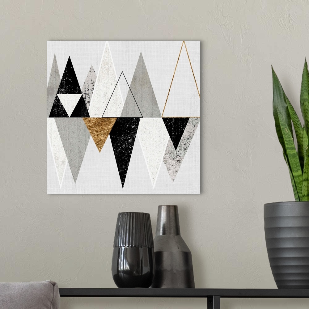 A modern room featuring Abstract art of two rows of triangles in black, grey, and gold.