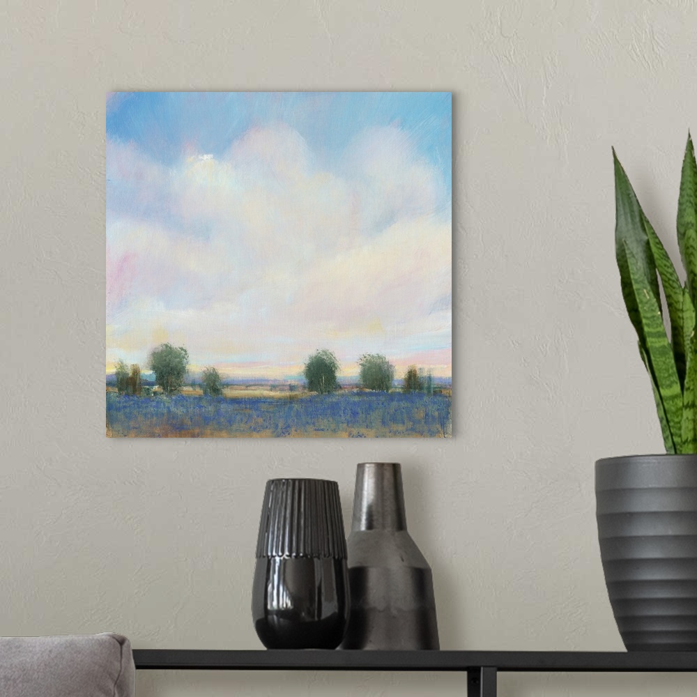 A modern room featuring Abstracted landscape painting with a field and trees below a cloudy, blue sky.