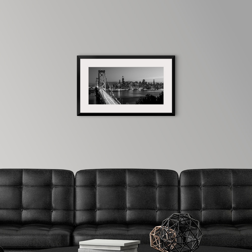 A modern room featuring Photograph of the Bay Bridge with a sunset and the San Francisco skyline lit up in the background.