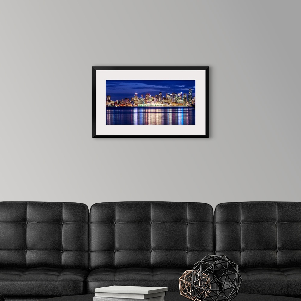 A modern room featuring Photograph of the Vancouver, British Columbia skyline lit up on a dark blue night and reflecting ...