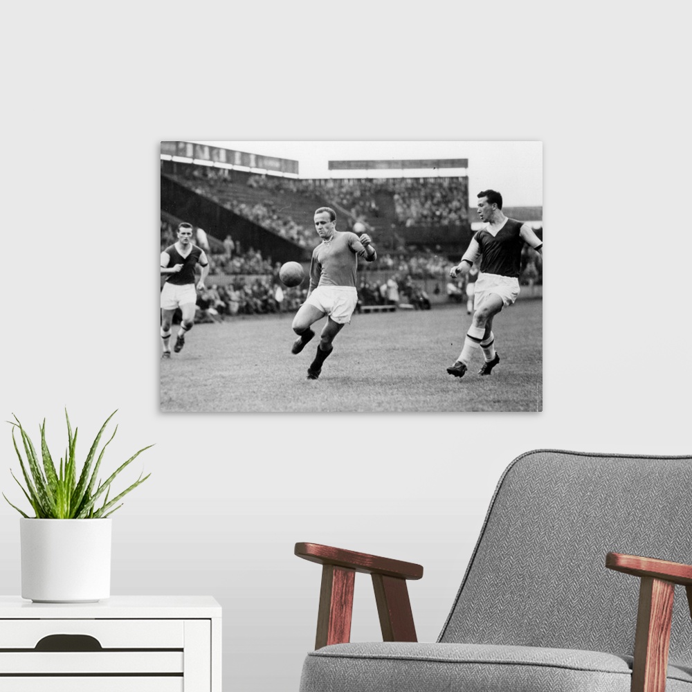 A modern room featuring 23rd May 1957:  Macek of Prague controls the ball during his team's game against West Ham United ...