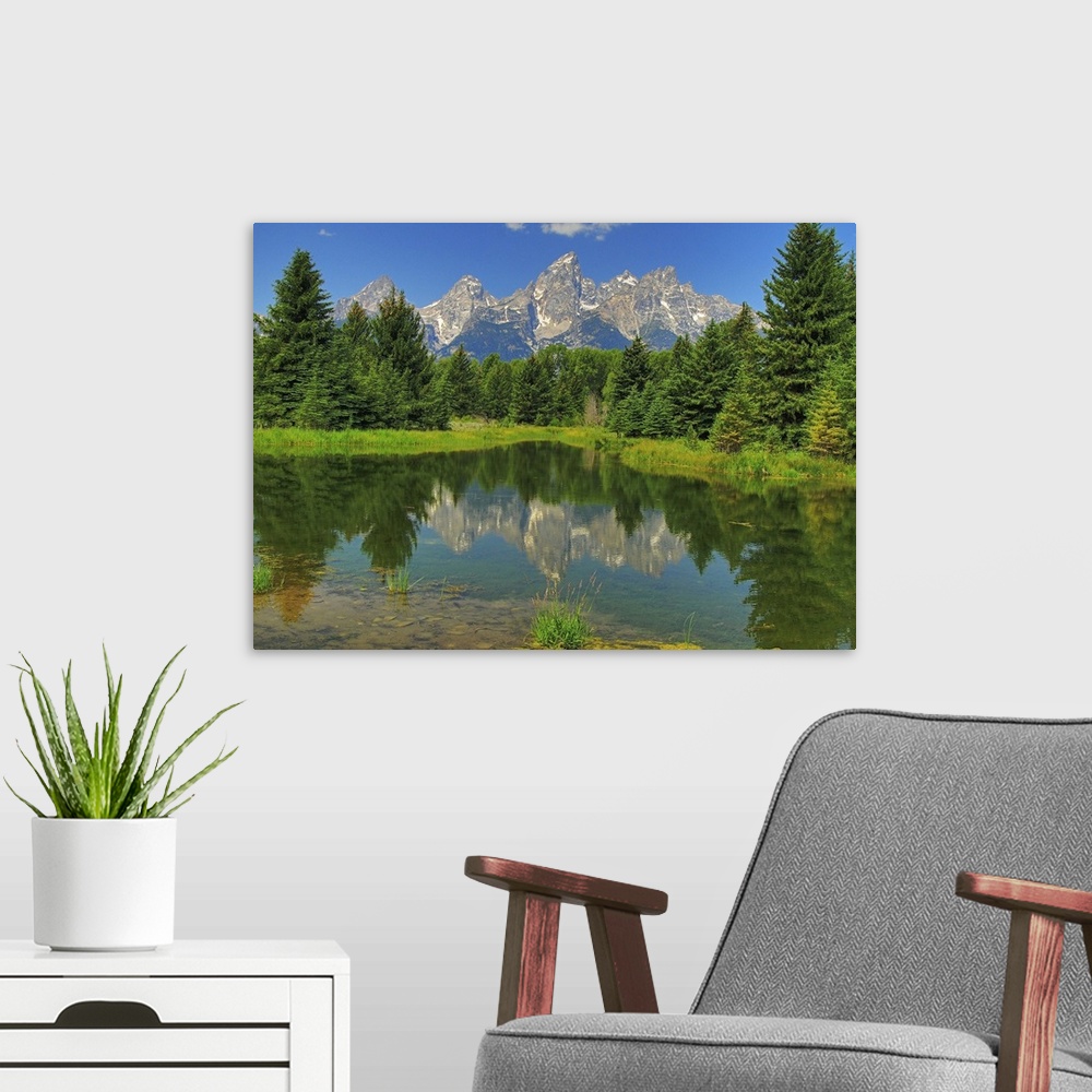 A modern room featuring Grand Teton mountains reflected on a still pond in Grand Teton National Park