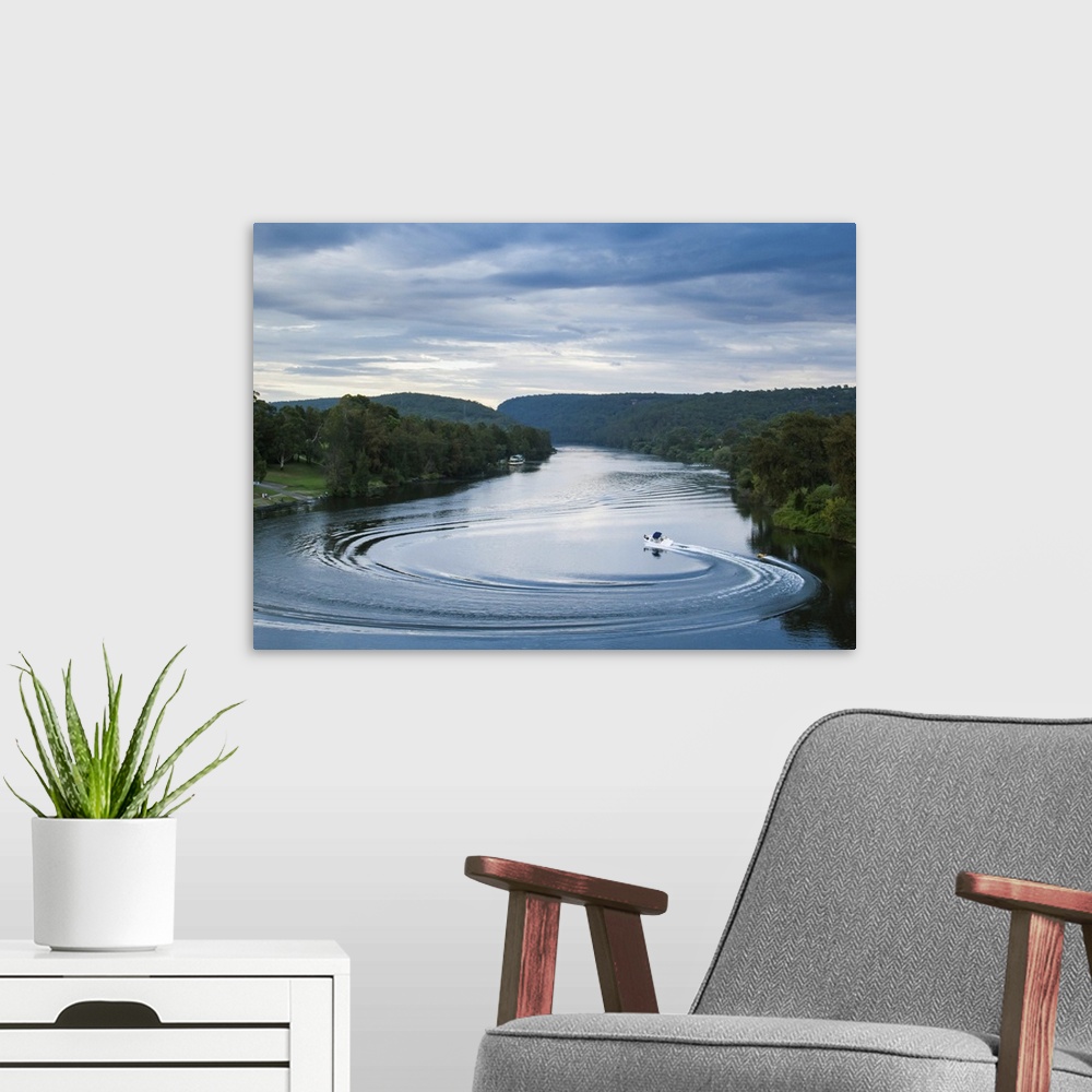 A modern room featuring A boat pulling a person on a raft makes a dramatic turn in the middle of the Nepean River at sunset.