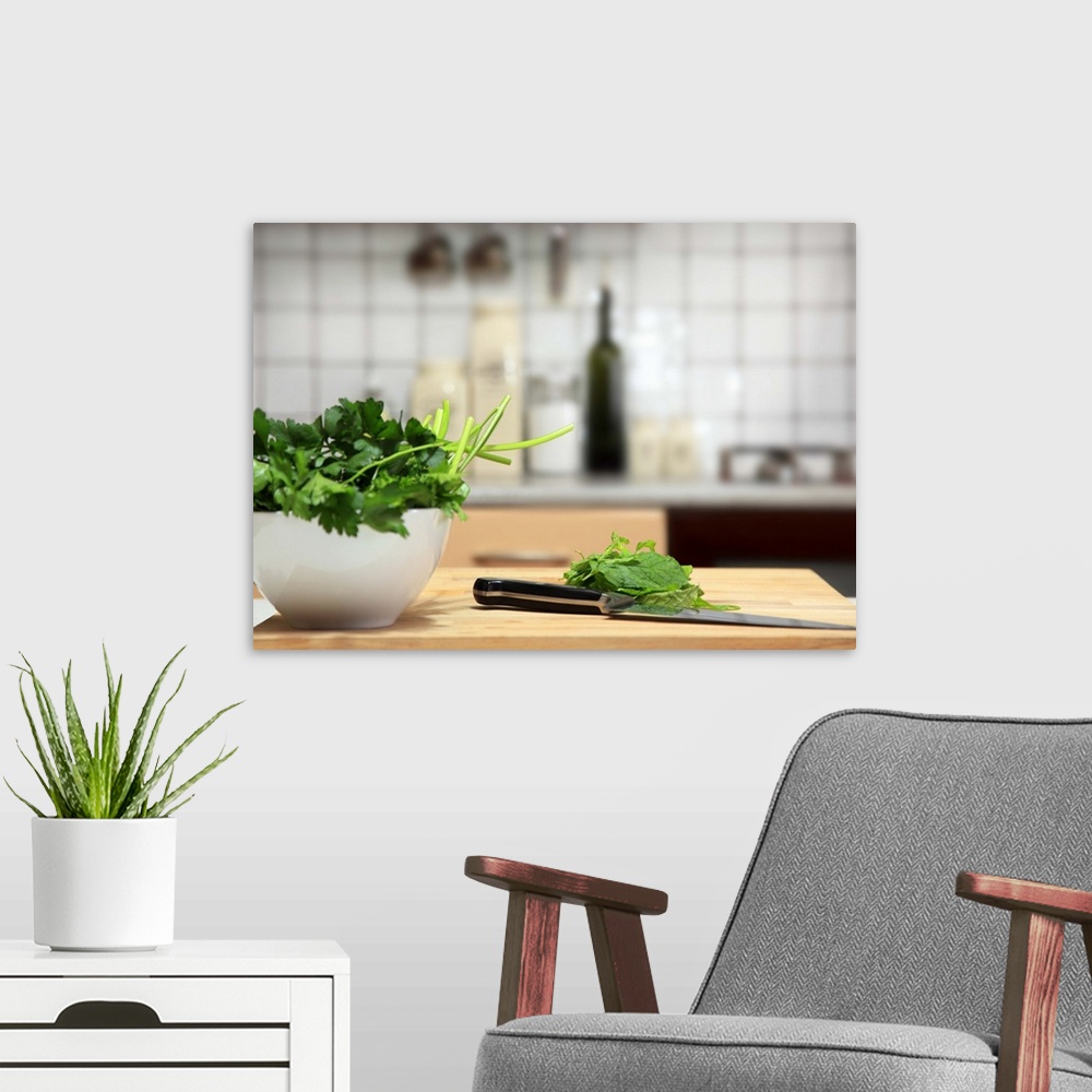 A modern room featuring Basil and parsley on a white bowl. There are also some herbs on a wooden surface, ready to be cut...