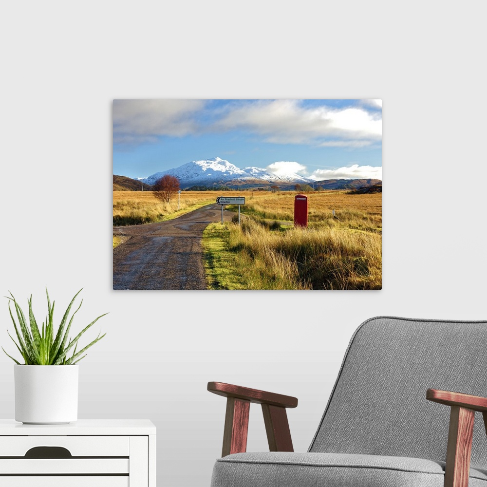 A modern room featuring Winter view of a red telephone box and road toward snow covered Beinn Resipol mountain in the moo...