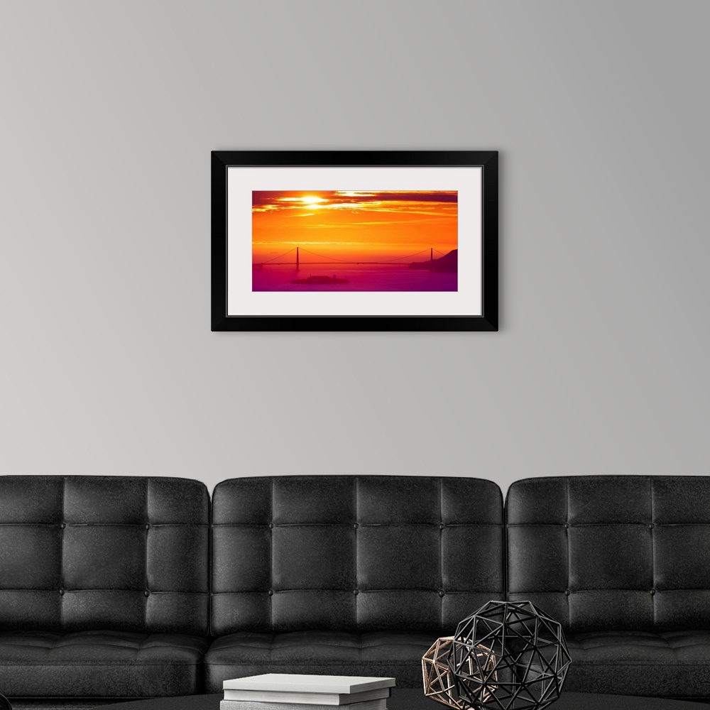 A modern room featuring A photograph of a vibrant sky at sunrise, with a bridge in hazy, misty morning light.