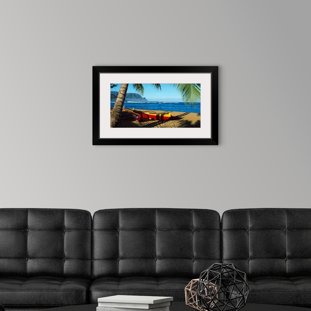 A modern room featuring Oversize wall art of a landscape photograph of a sailboat pulled up the shore and resting in the ...