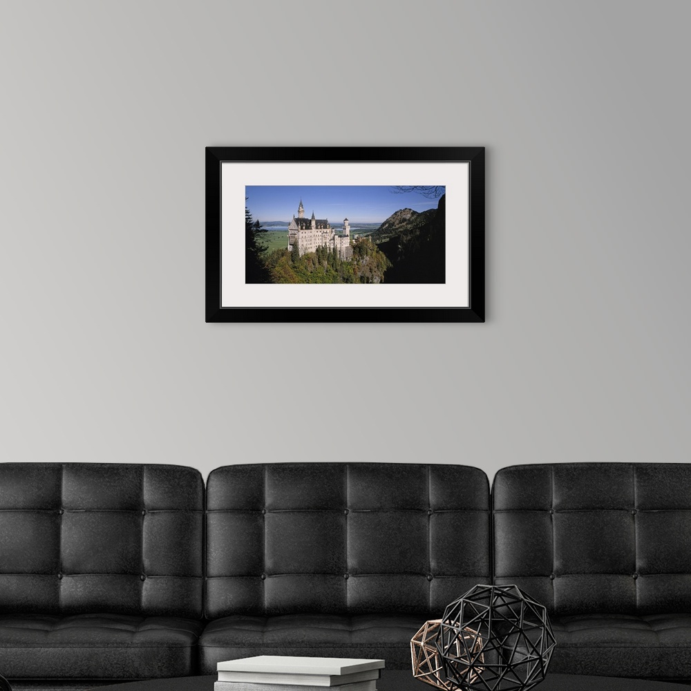 A modern room featuring A landscape photograph of an elegant caste build on top of a steep, tree covered hill.