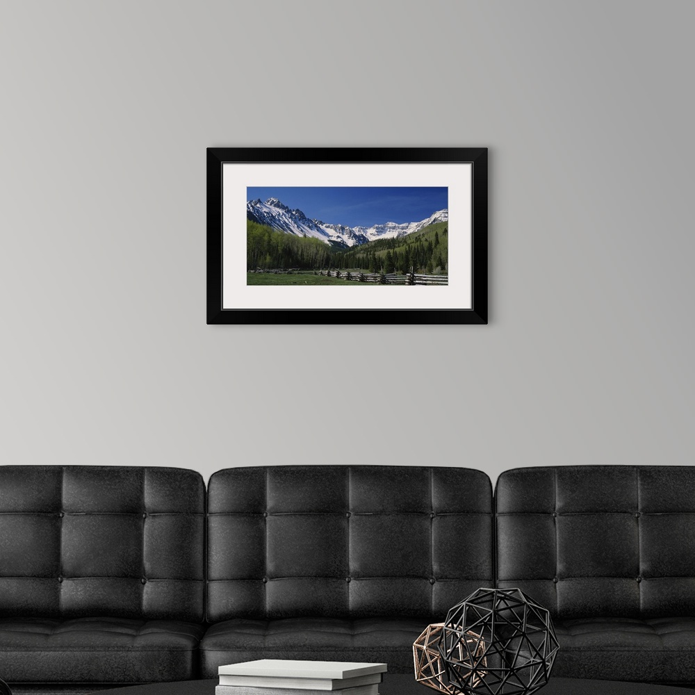 A modern room featuring Photo of a fenced field surrounded by a thick forest and mountain range in San Juan Mountains, Co...