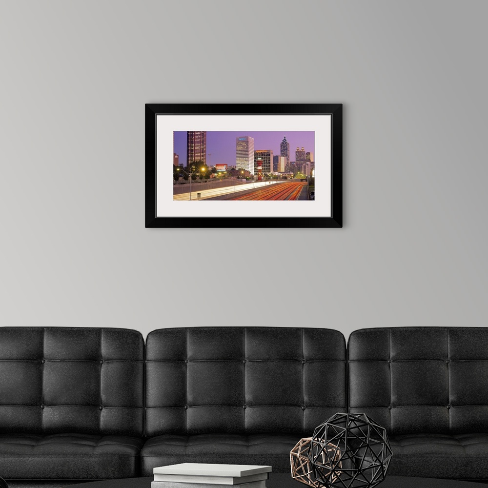 A modern room featuring Panoramic photograph of highway filled with light trails lined by lit up buildings at sunset.