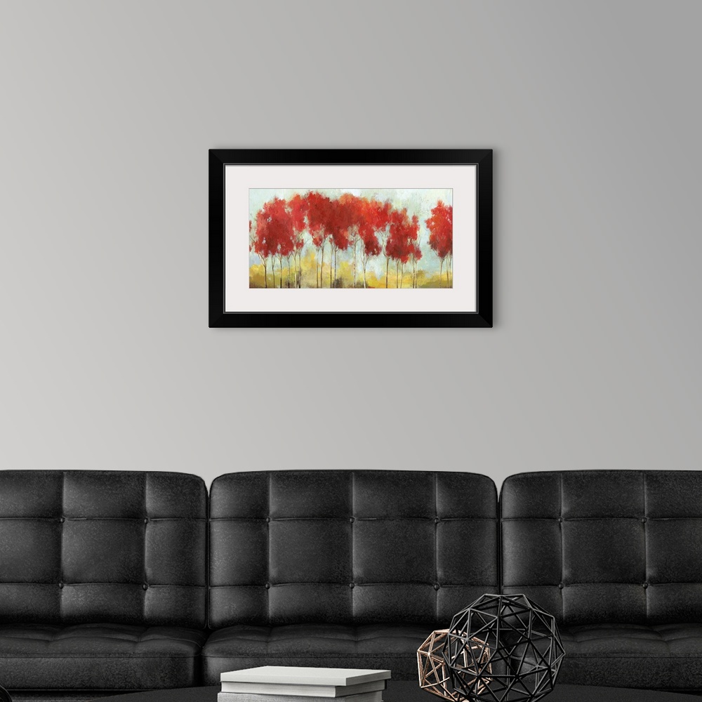 A modern room featuring A long horizontal painting of a row of trees with bright red leaves in the fall.