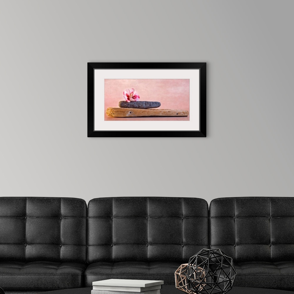 A modern room featuring Decorative artwork that has a plank of wood with a stone on top of it and a hibiscus flower on to...