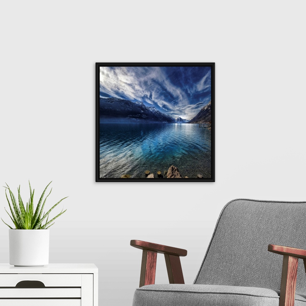 A modern room featuring This square shaped decorative wall art is a landscape photograph of a lake surrounded by snow cov...