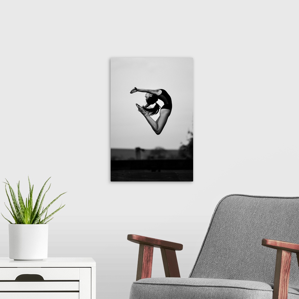 A modern room featuring A dancer leaping into the air, arching her back.