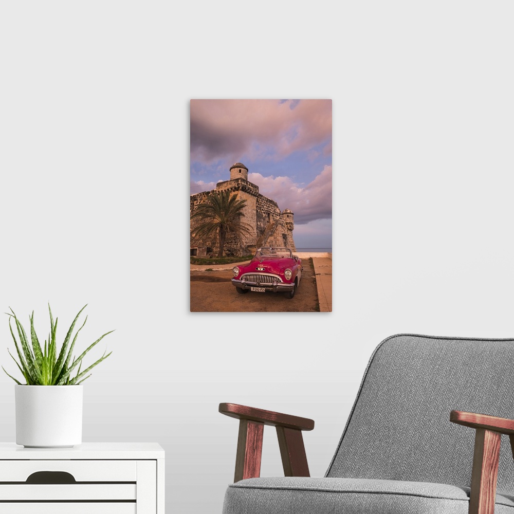 A modern room featuring Cuba, Cojimar. Classic American car parked in front of a fort.