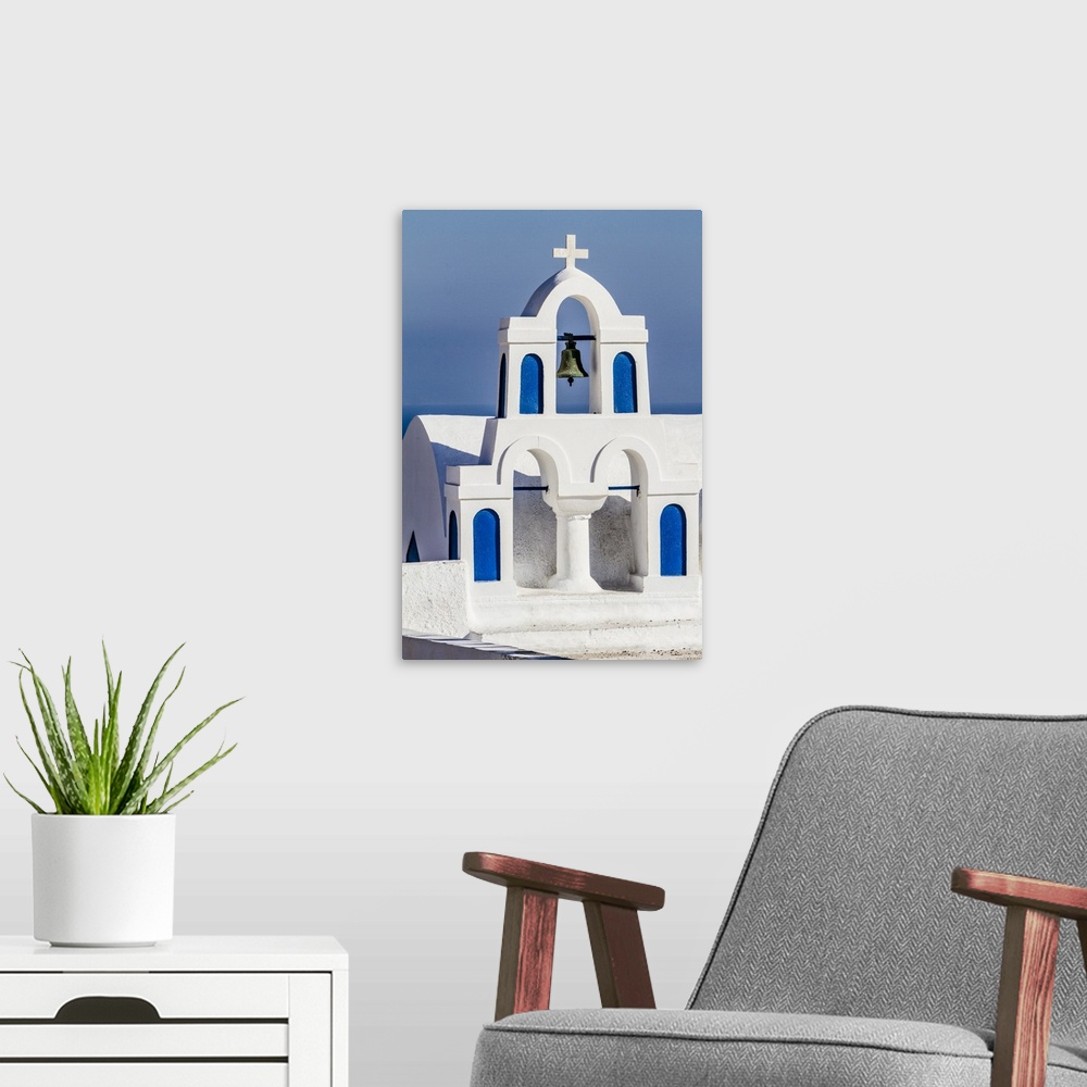A modern room featuring Oia, Greece. Greek Orthdox Church steeple, cross, bell, and blue arches against Aegean Sea.
