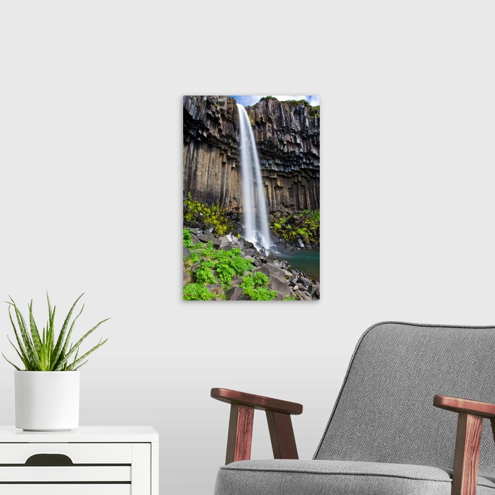 A modern room featuring Svartifoss, a waterfall in southern Iceland, cascades over ancient basaltic columns.