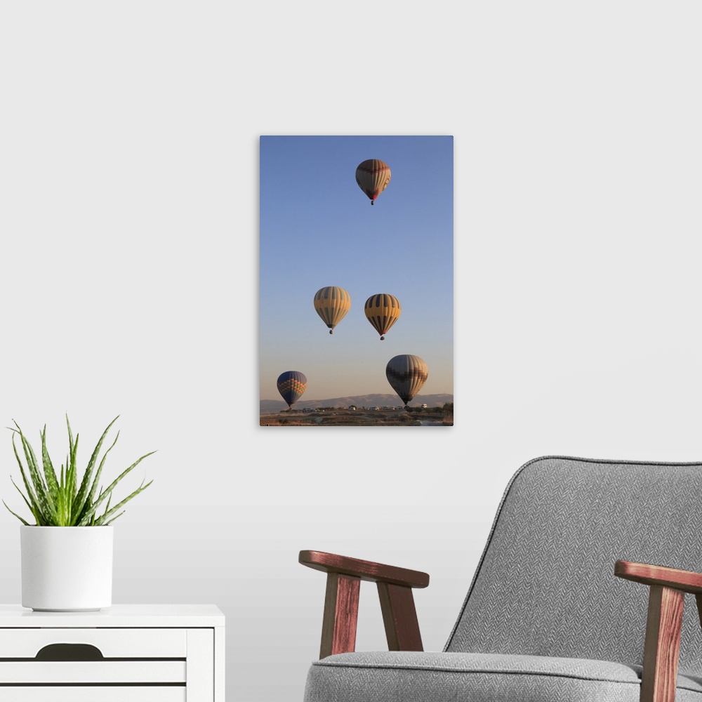 A modern room featuring Turkey,Anatolia,Cappadocia, Goreme. Hot air balloons flying above/among rock formations and field...