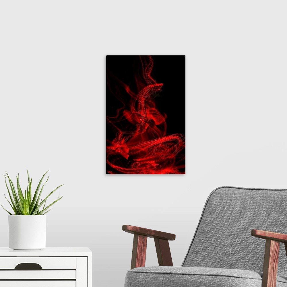 A modern room featuring Long exposure abstract photograph of red light trails resembling smoke with a black background.
