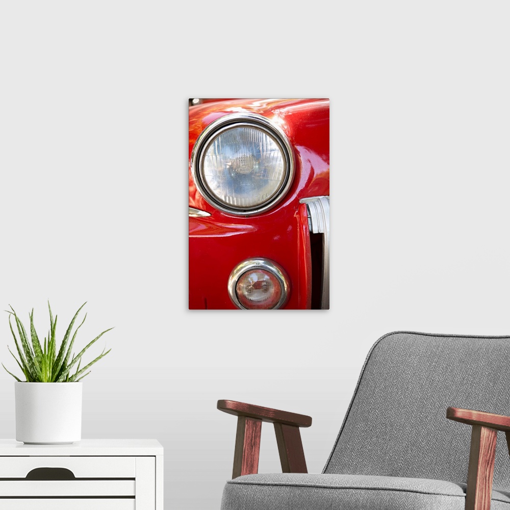 A modern room featuring Close-up photograph of the headlight of a red vintage car in Cuba.