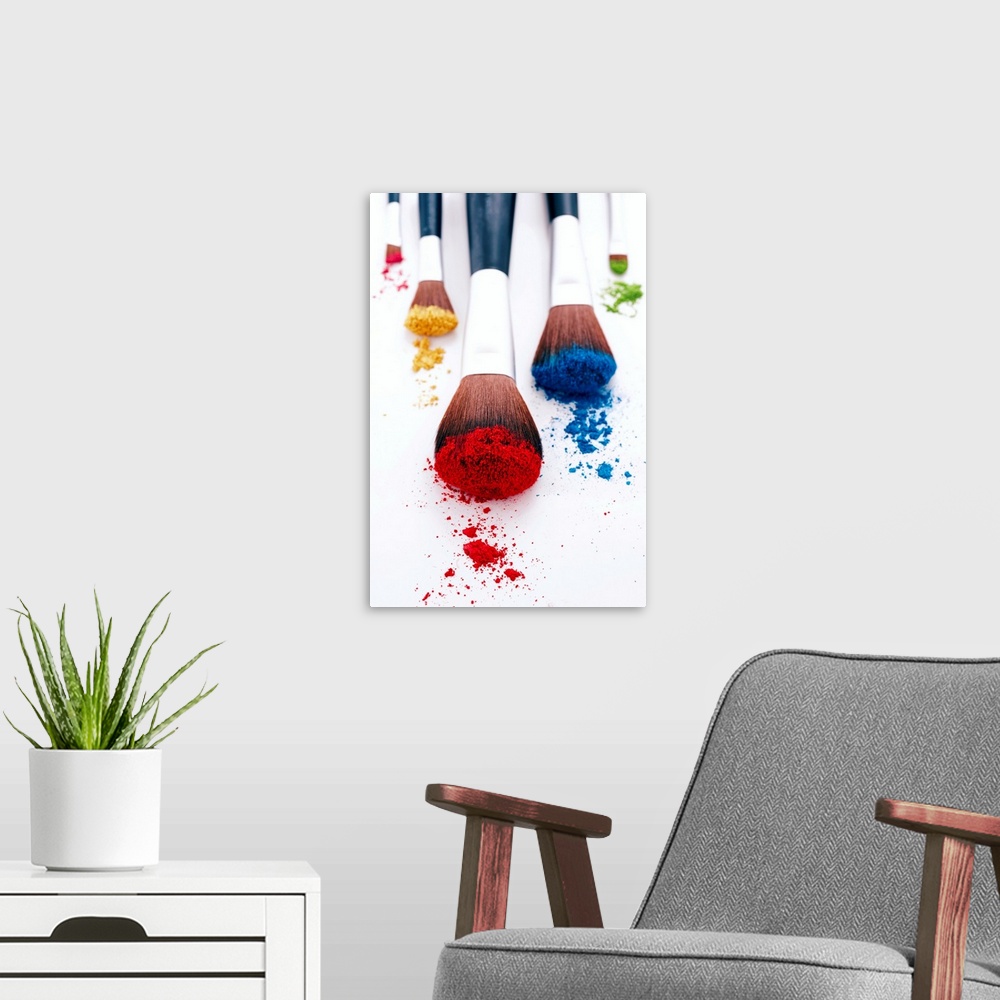 A modern room featuring A vertical photo of makeup brushes heavily filled with pigment resting on blank a surface.