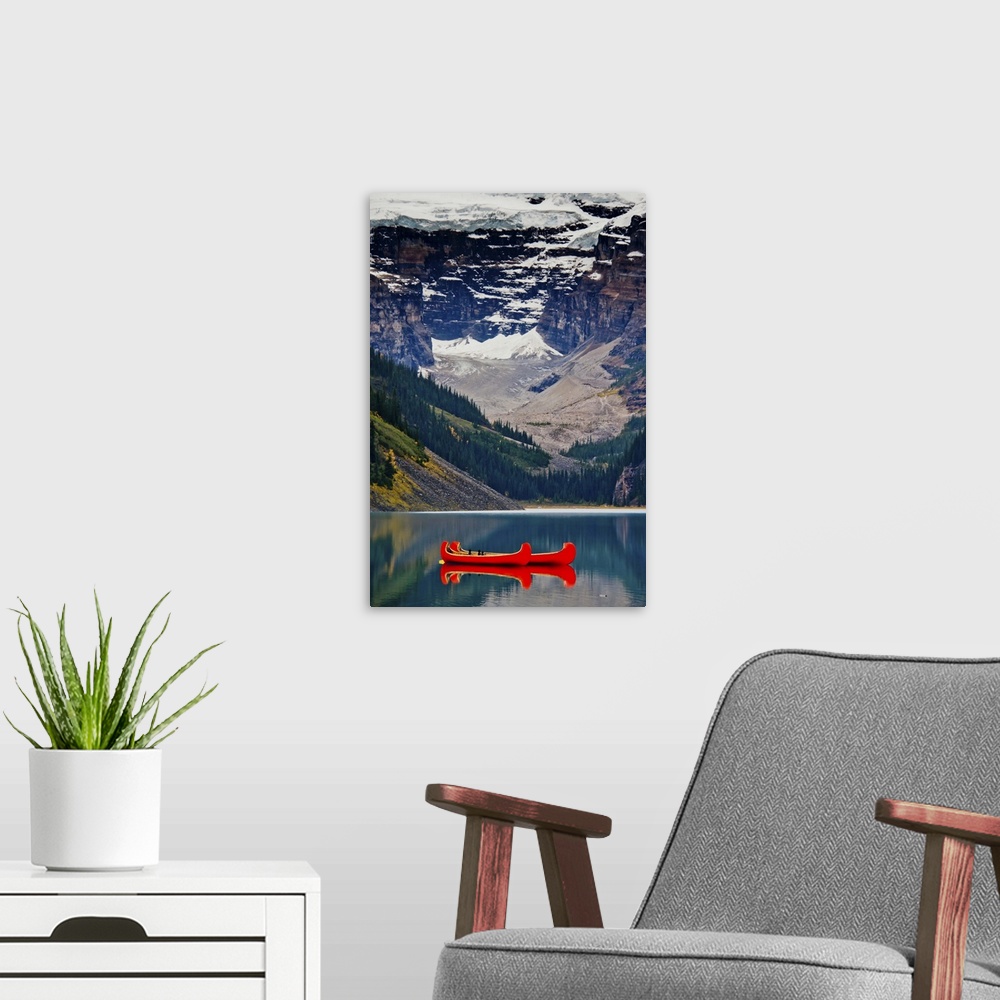 A modern room featuring Lake Louise, British Columbia Canada. Red canoe on the lake in front of glacier & snowy mountains.