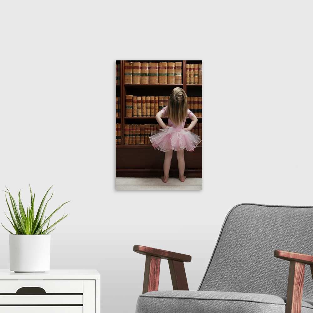 A modern room featuring Little girl in tutu reading book covers in library