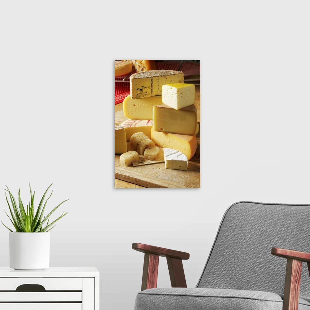 A modern room featuring Big, vertical photograph of stacks of assorted light yellow and white cheeses, sitting on a woode...