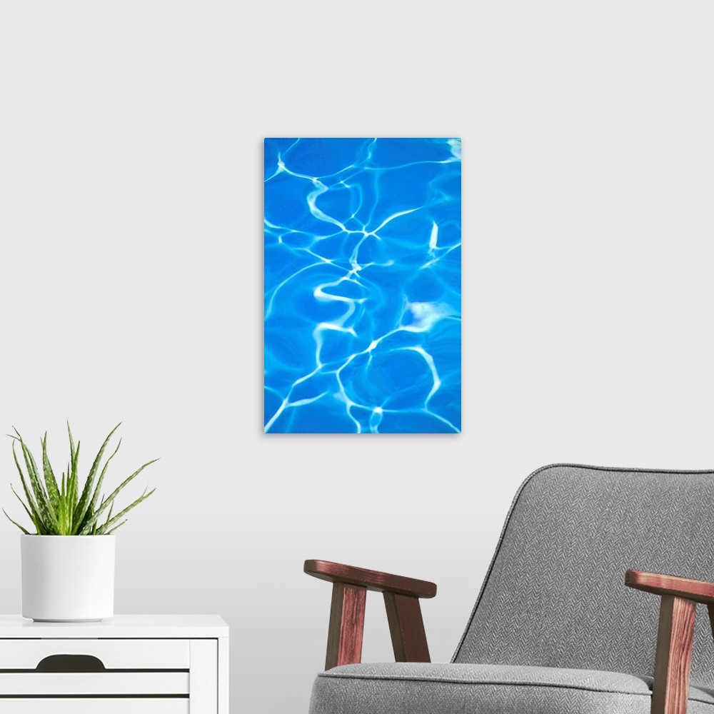 A modern room featuring Vibrant blue swimming pool with light refracted through water.